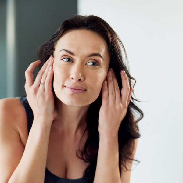 Cropped shot of an attractive woman admiring her face in the bathroom mirror